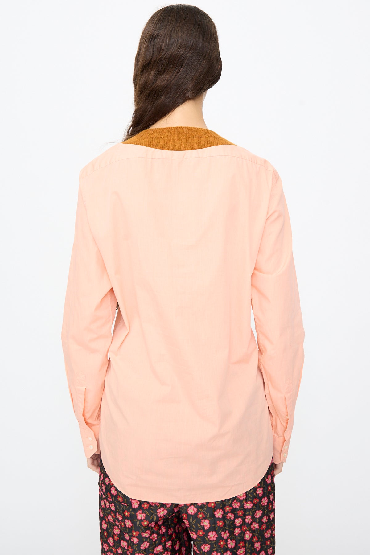 Back view of a person wearing a light pink No. 68 Frontinsertpullover in Unique V, featuring a long-sleeved button-up design with a dark brown Shetland wool knit collar insert.