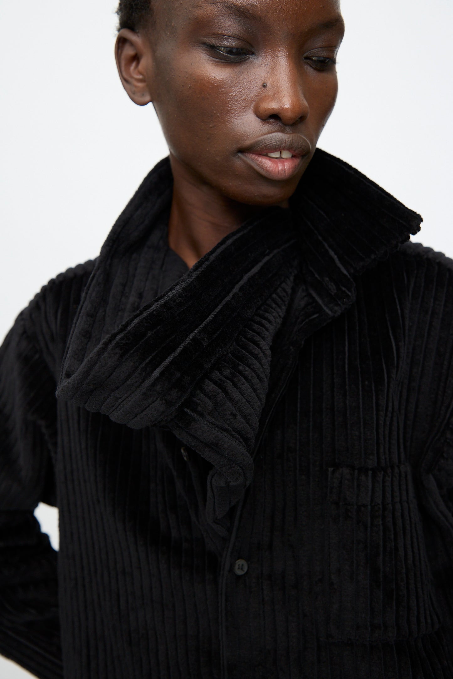 A person wears the Bless No. 68 Neckerchiefer in black corduroy, styled like a ribbed velvet jacket with a wide collar, looking down against a plain background.