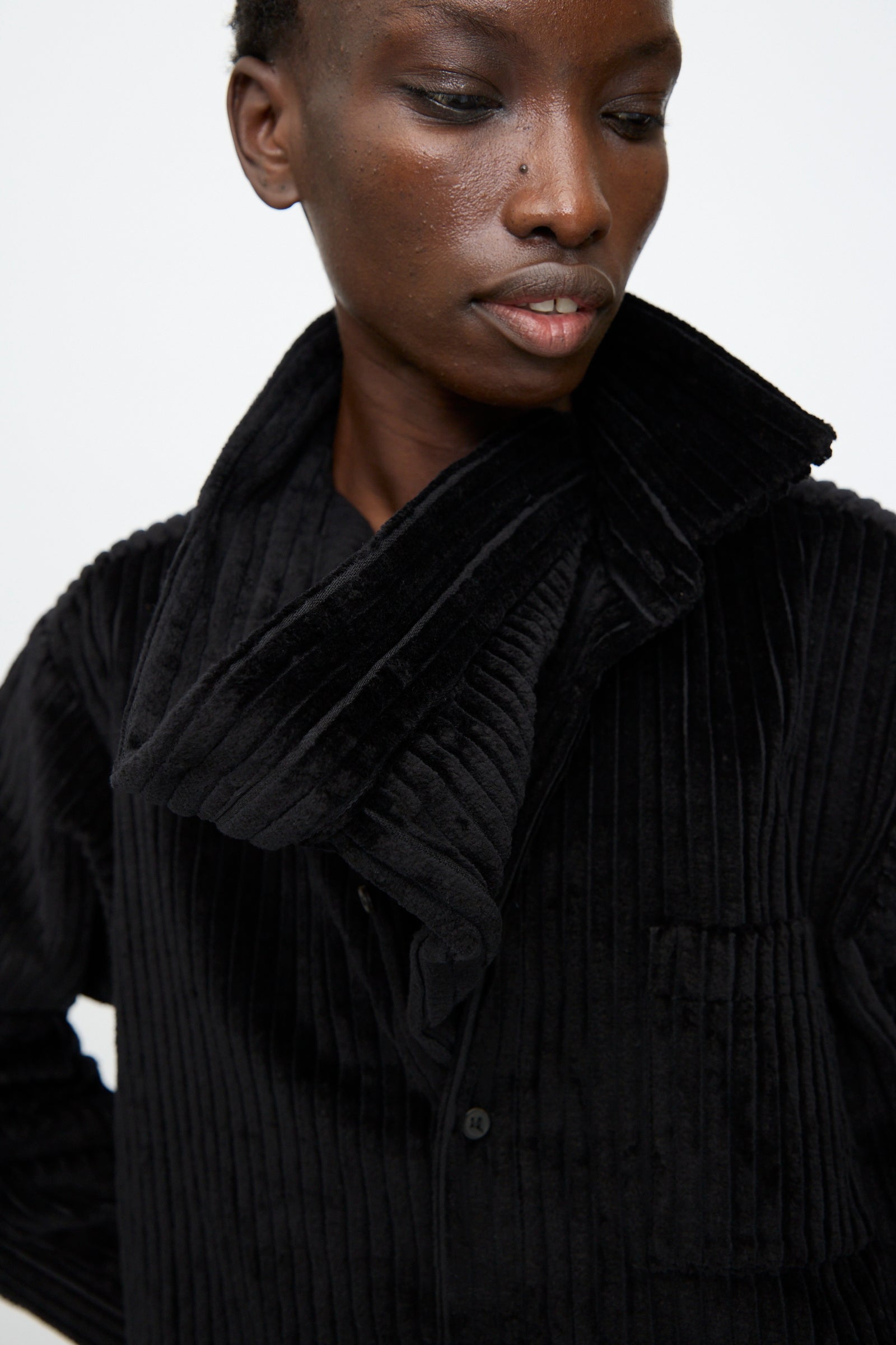 A person wears the Bless No. 68 Neckerchiefer in black corduroy, styled like a ribbed velvet jacket with a wide collar, looking down against a plain background.