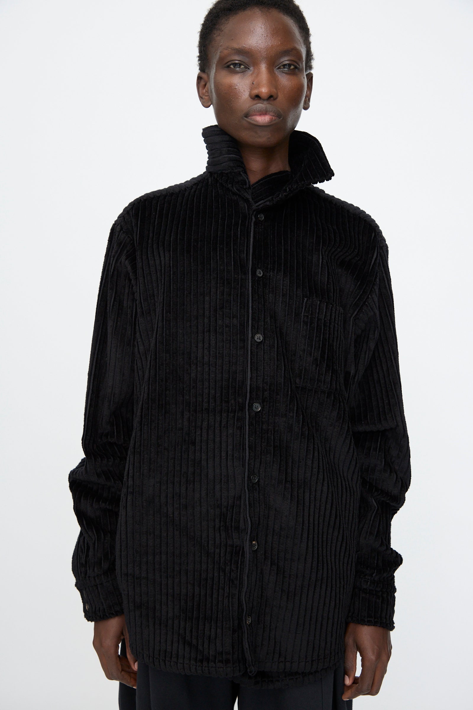 A person faces forward against a plain white background, wearing the Bless No. 68 Neckerchiefer in black corduroy with the collar turned up.