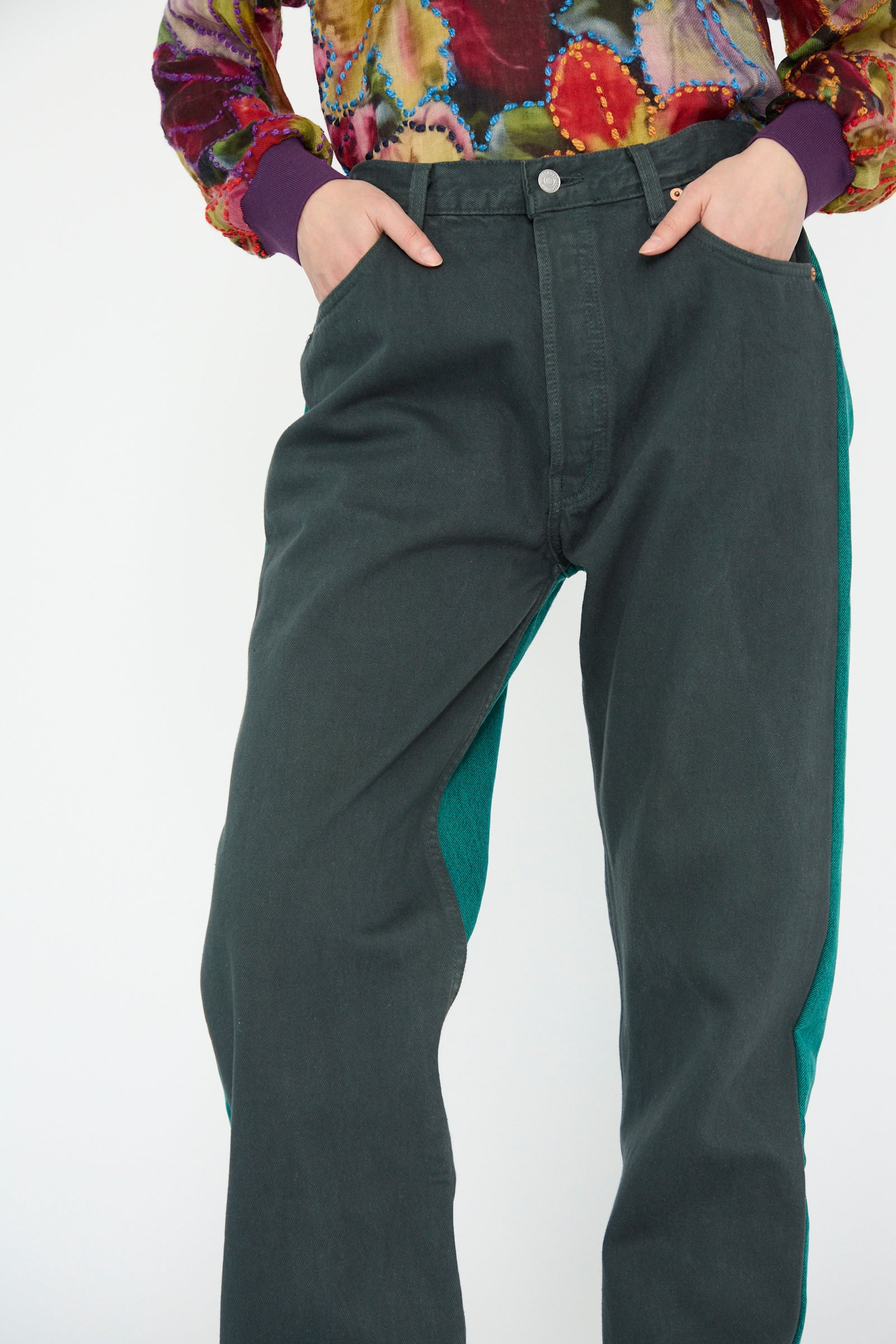 A person is wearing the No. 73 Jeanspleatfront in Surprise IV by Bless—straight-leg dark green pants in a relaxed fit, hands in pockets against a plain background.