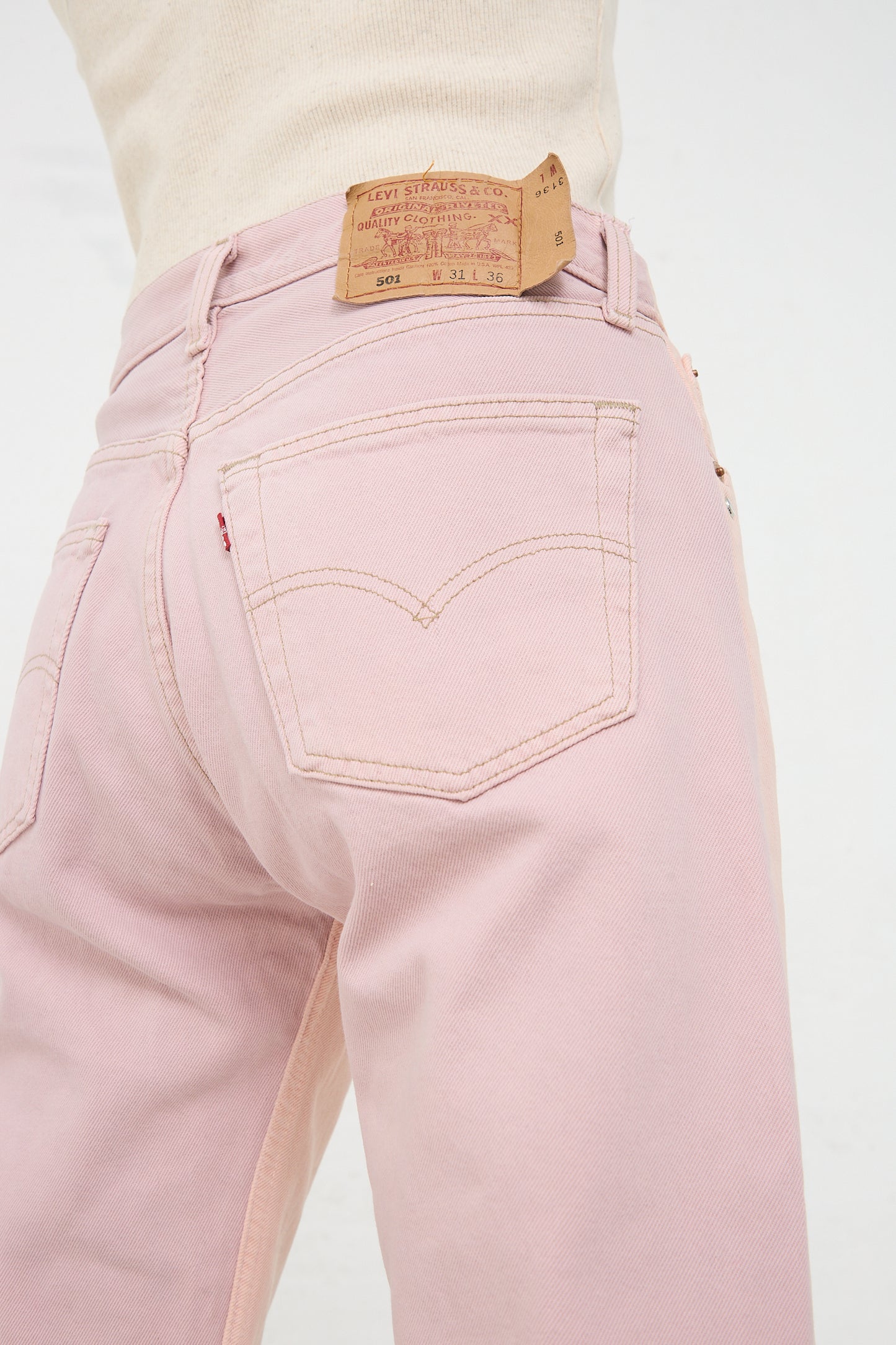 Close-up of Bless No. 73 Jeanspleatfront in Pink/Purple denim jeans with a leather brand patch on the waistband.