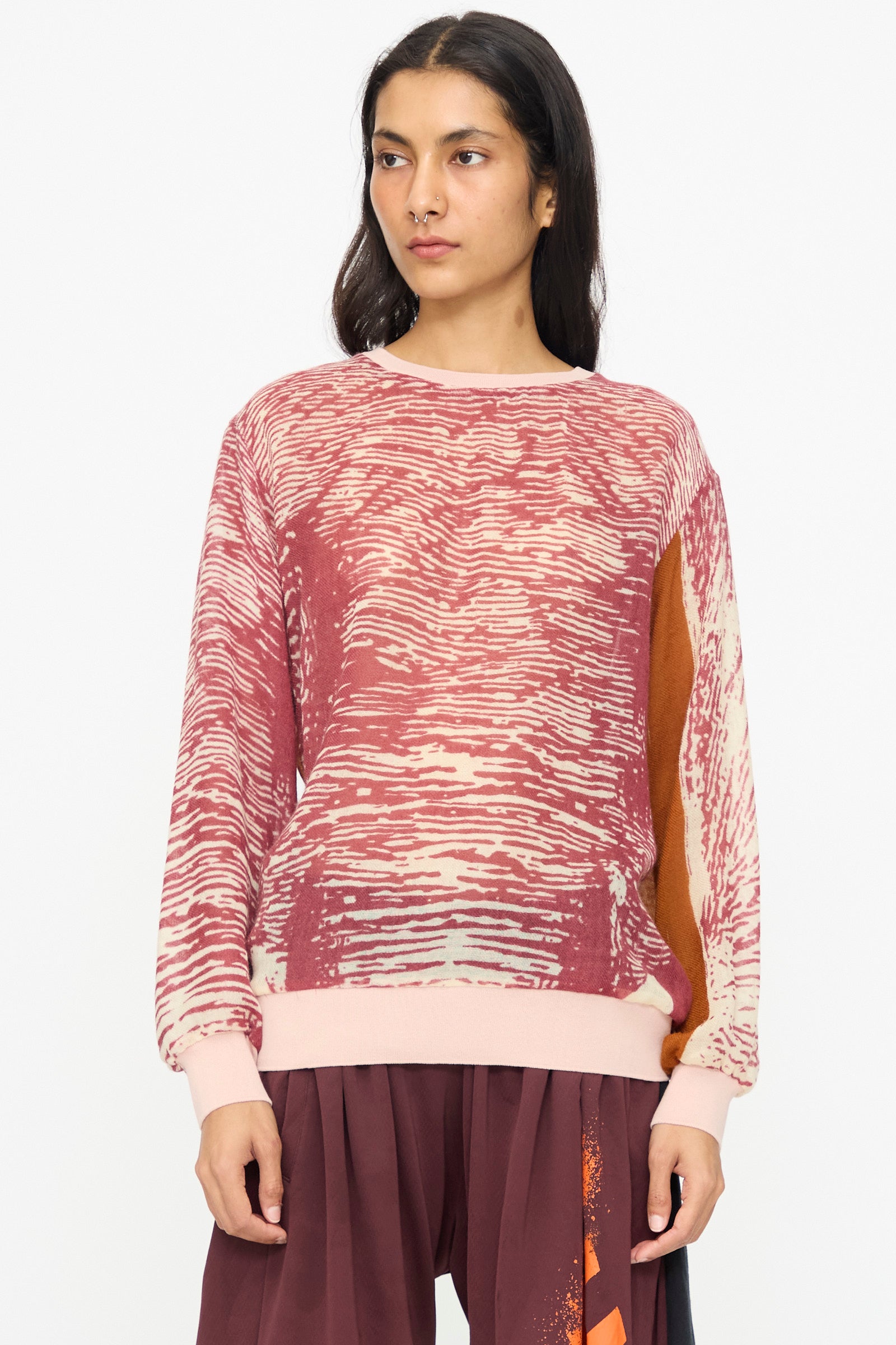 A person wears the Bless No. 81 M-Sweater in Exelephant, a maroon and cream elephant skin print lightweight sweater with long sleeves, paired with matching maroon pants, standing against a plain white background.