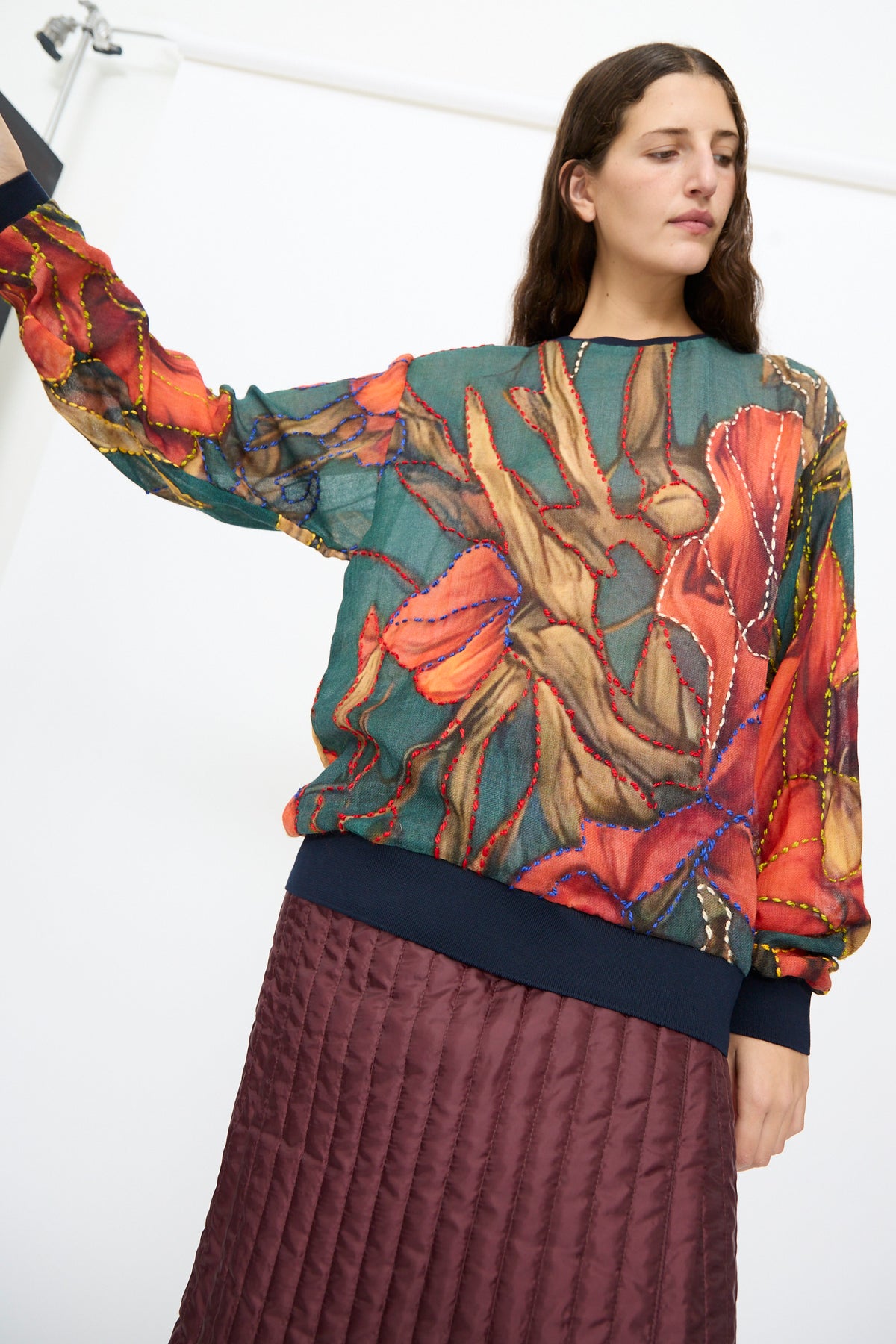 Bless No. 82 Embroidered Sweater in Dark Brown and Green featuring a lightweight floral print with contrast-stitch embroidery, paired with a dark maroon quilted skirt.
