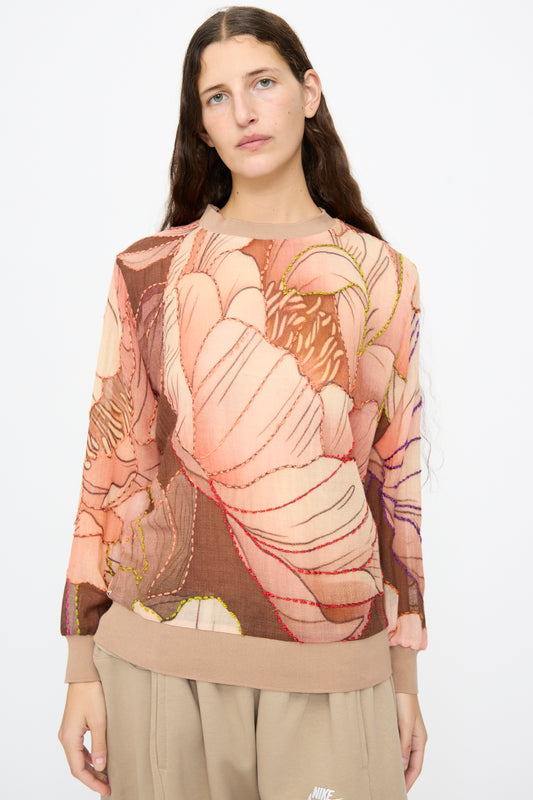 A woman wearing a Bless No. 82 Embroidered Sweater in Multicolor Beige and Rosé, a long-sleeve, floral print wool sweater with an abstract pink and brown pattern and prominent decorative stitching.