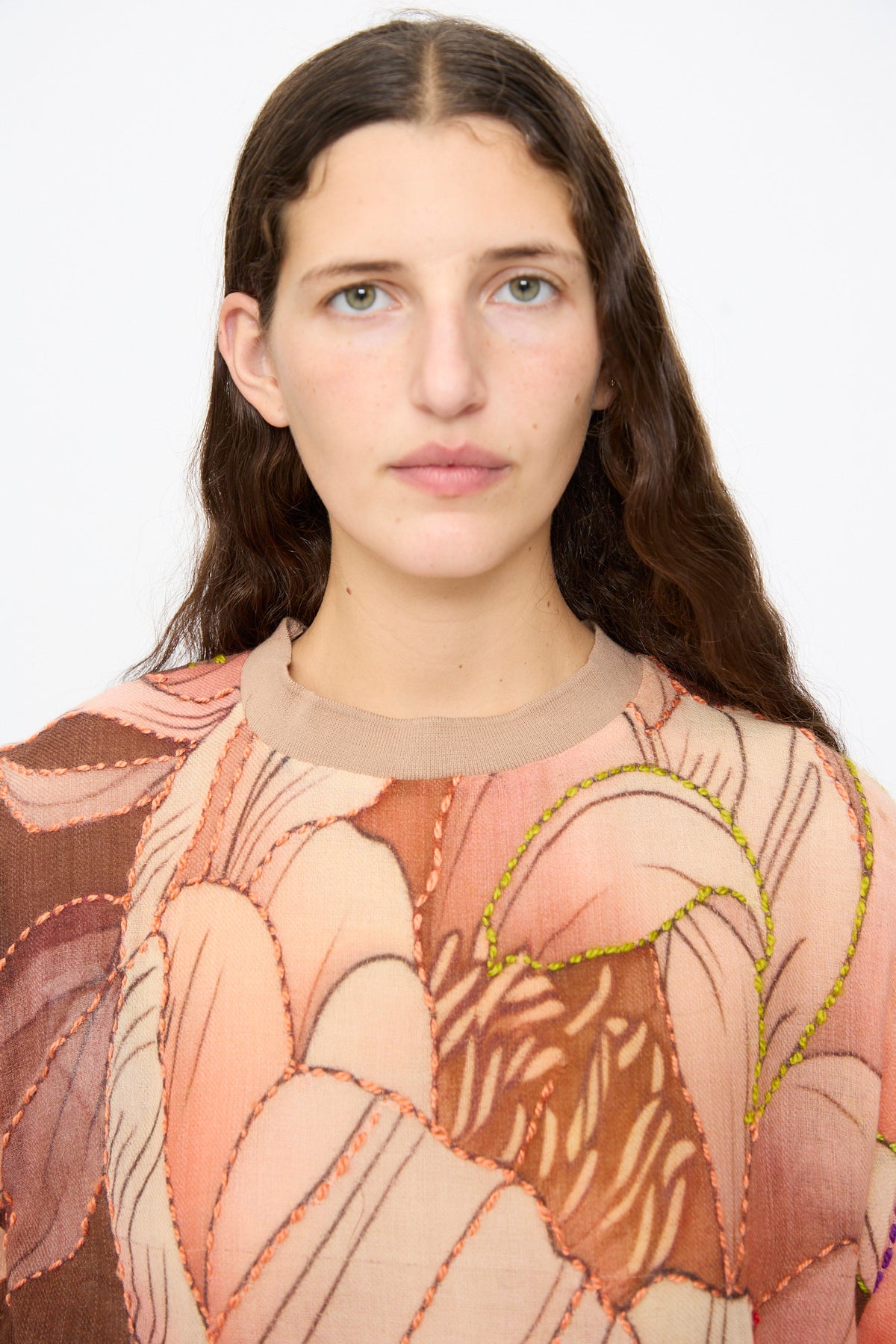 Close-up of a person wearing the Bless No. 82 Embroidered Sweater in Multicolor Beige and Rosé, featuring large abstract floral embroidery in orange and lime green thread.