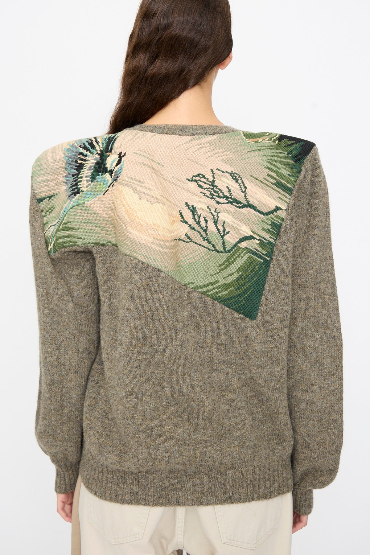 A long-sleeved gray wool Bless No. 82 Kitschenrich in Unique Ultralarge Patchwork I pullover sweater featuring an angled, tapestry-style needlepoint motif on the upper back of a bird and foliage.