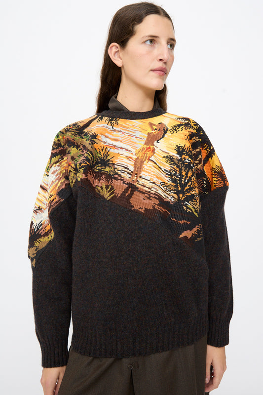 Person wearing a Bless No. 82 Kitschenrich in Unique Ultralarge Patchwork II wool pullover sweater with a brown base and a graphic landscape needlepoint motif across the chest and shoulders.