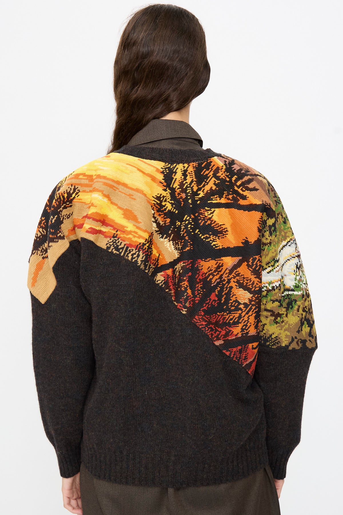 Back view of the Bless No. 82 Kitschenrich in Unique Ultralarge Patchwork II wool pullover, featuring diagonal panels of knit-in landscape scenes depicting a sunset and trees.