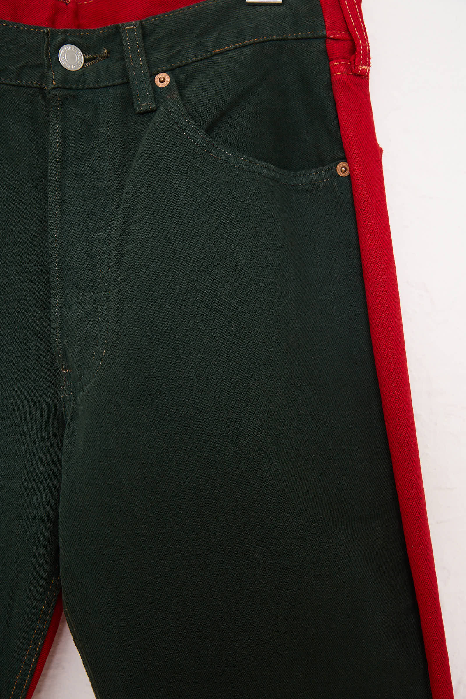 Close-up of the No. 73 Jeanspleatfront by Bless, featuring a mid-waist fit with one leg in black and the other in red, showcasing a relaxed fit, contrasting color design, and detailed front pockets.