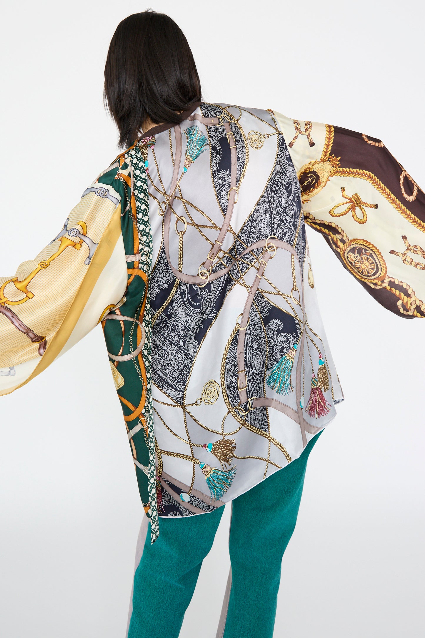 A model is shown from the back, wearing the Bless Windy Silkscarves Top in Green Brown Yellow Prints II with green pants against a plain background.