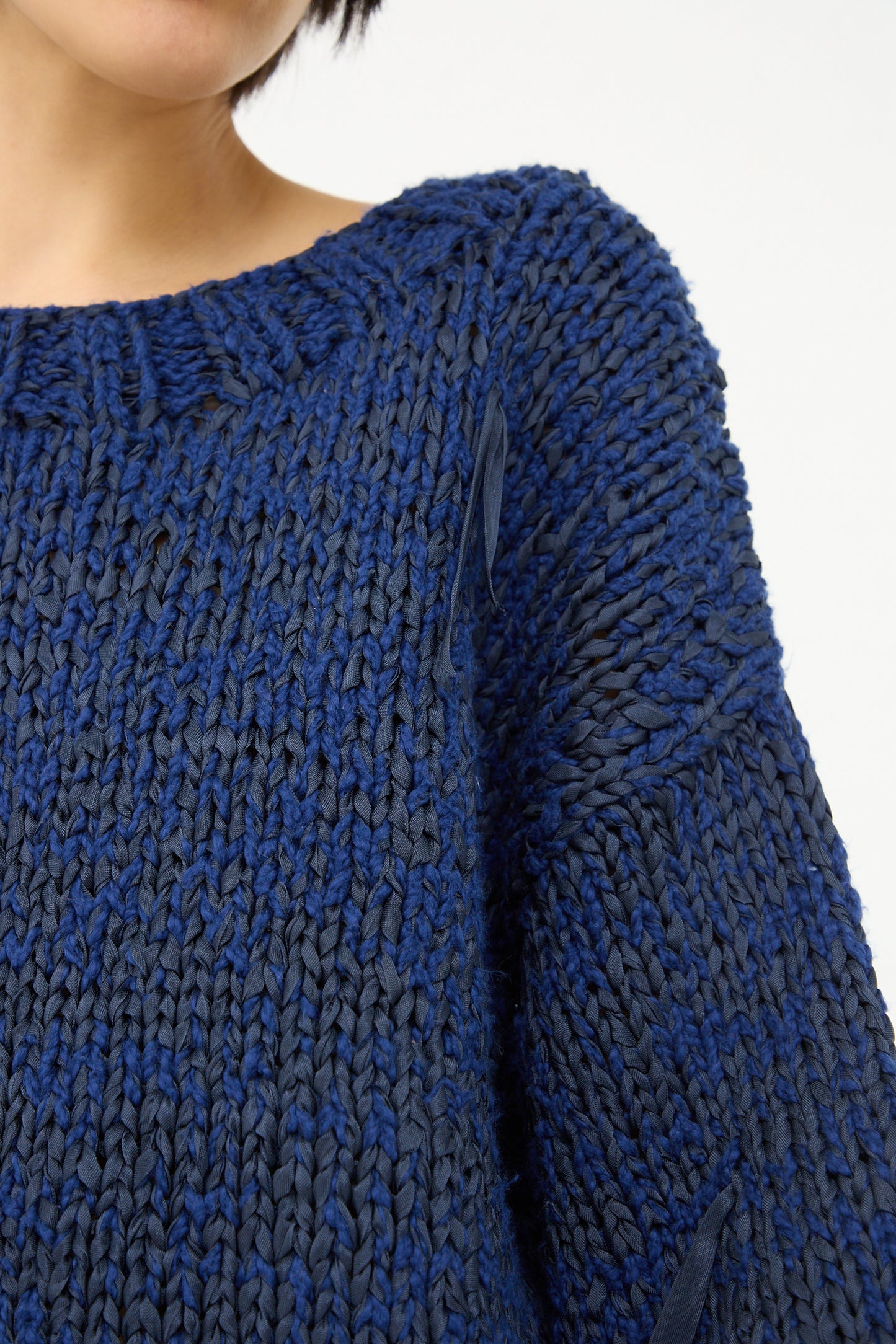 Close-up of a person wearing a Caron Callahan Boucle Cotton Yarn Hampton Sweater in Indigo.