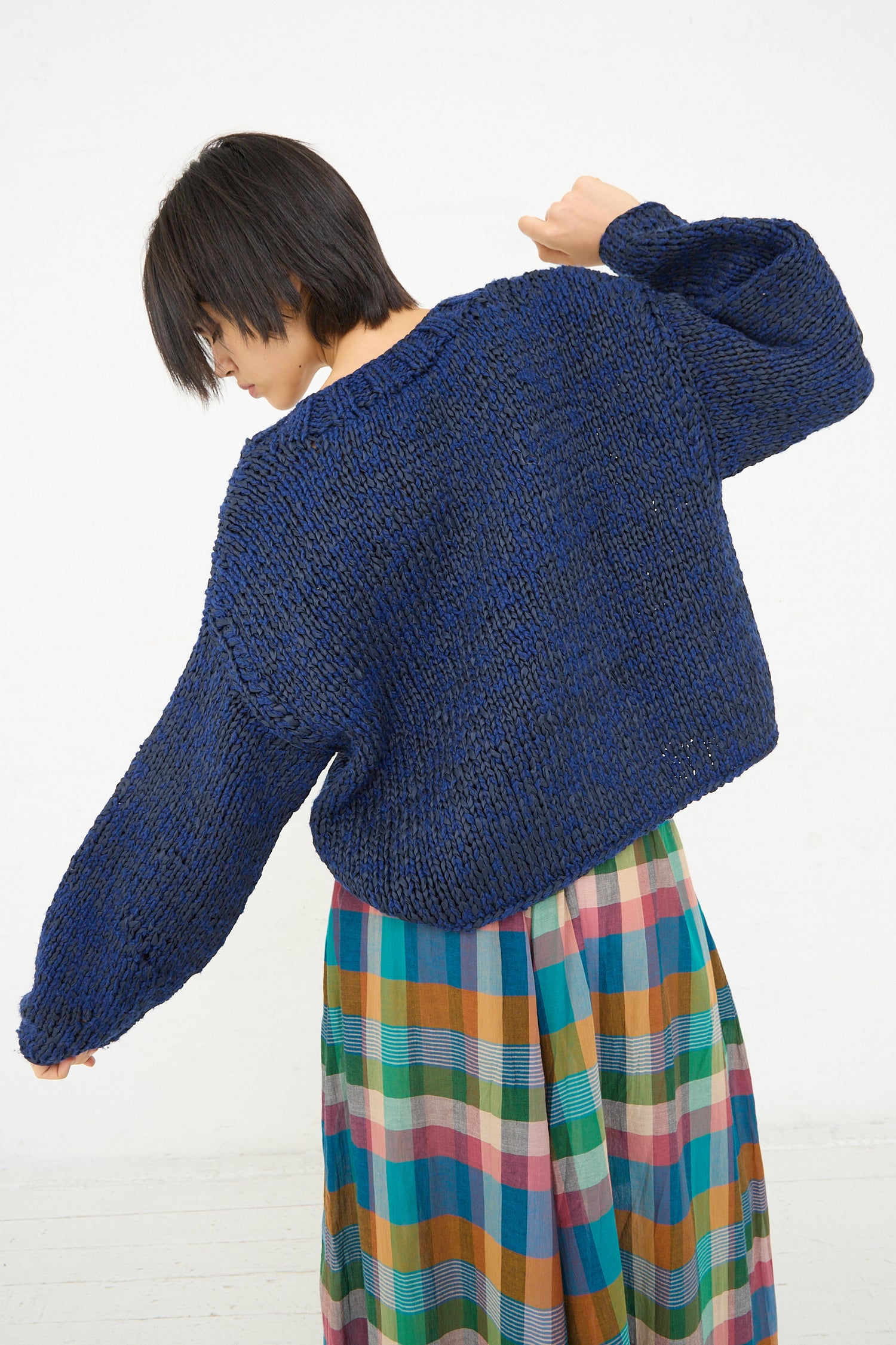 Woman in a Caron Callahan Boucle Cotton Yarn Hampton Sweater in Indigo and colorful skirt with her back turned.
