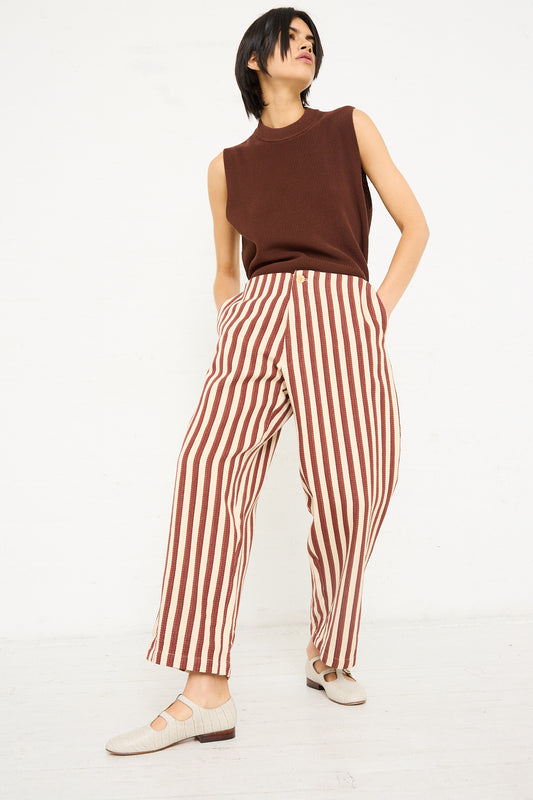 A woman stands in a casual pose wearing Caron Callahan's Dexter Pant in Auburn Stripe and sleeveless brown top, with her hand tucked into a pocket.