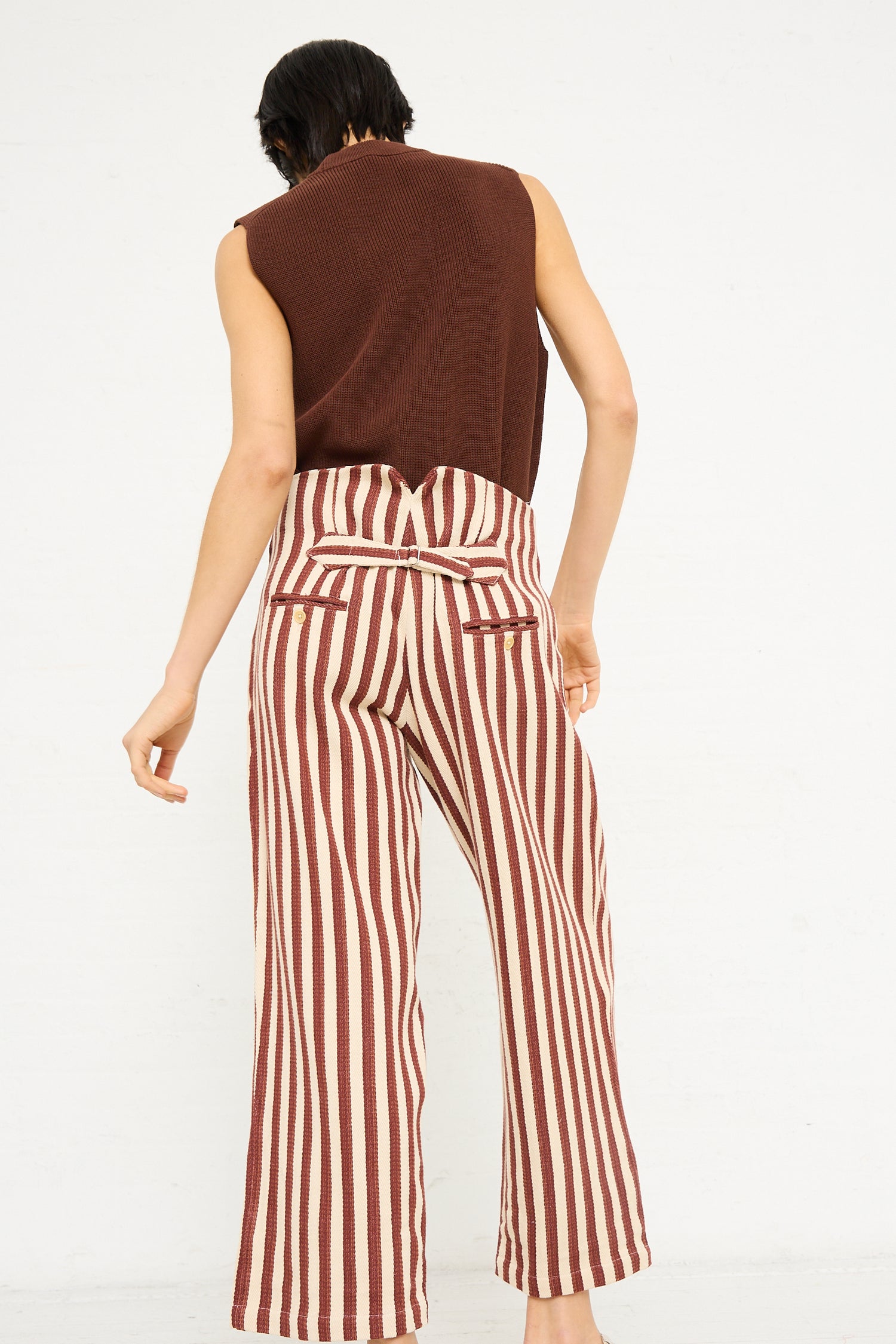 Woman standing with her back to the camera, wearing Caron Callahan's Dexter Pant in Auburn Stripe and a brown sleeveless top.