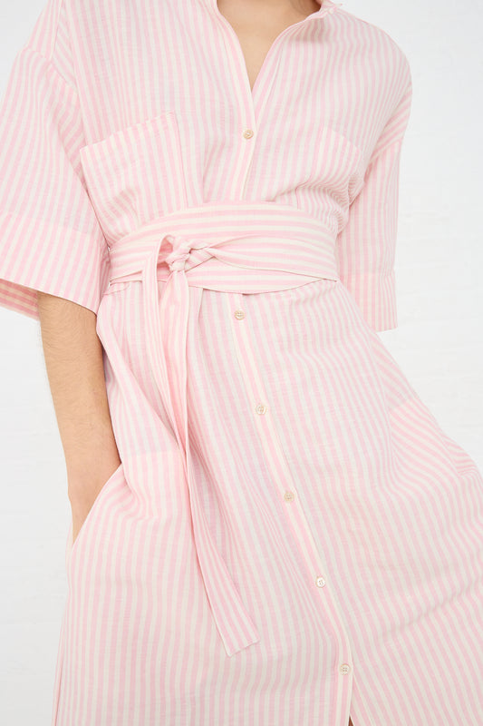 Mid-section of a person wearing a Caron Callahan Linen Stripe Kalloni Dress in Pink - pink stripe and white oversized shirt dress with buttons and a waist tie, crafted from a linen blend.