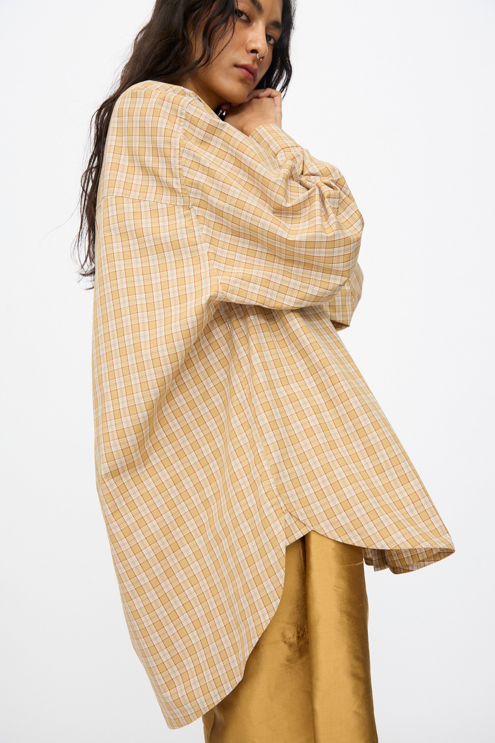 A person wears the Cawley Checked Cotton Phoebe Shirt in Ochre, Red and Purple Check, styled over a gold satin skirt and standing against a plain background.