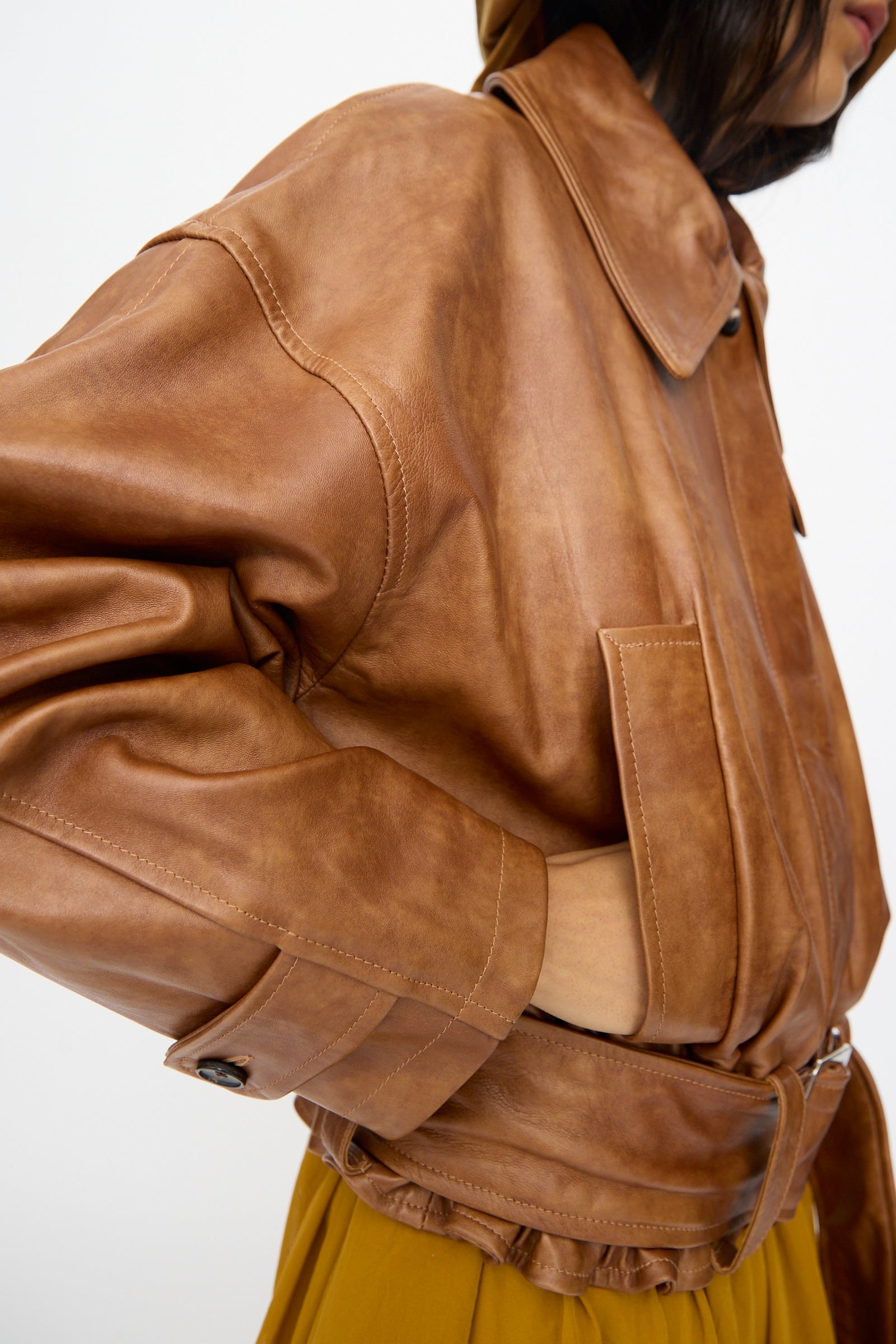 A person wearing the Cawley Holborn Leather Nara Jacket in Tan, with one hand in the pocket, is shown from the side against a plain background.