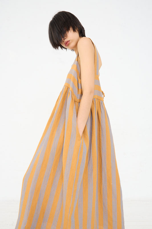 A woman is seen posing in a sleeveless striped Cawley linen dress with her head tilted down, partially obscuring her face with her dark bob haircut.