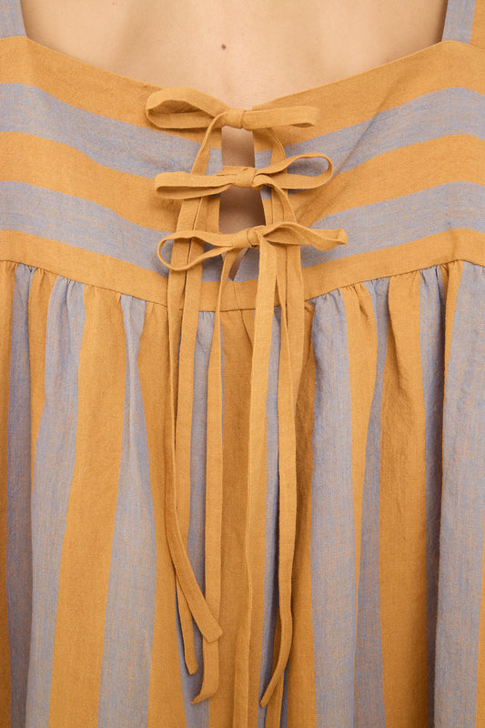 Close-up of an Irish Linen Elba Dress in Bronze by Cawley featuring a blue and tan striped pattern with a tie detail at the center.