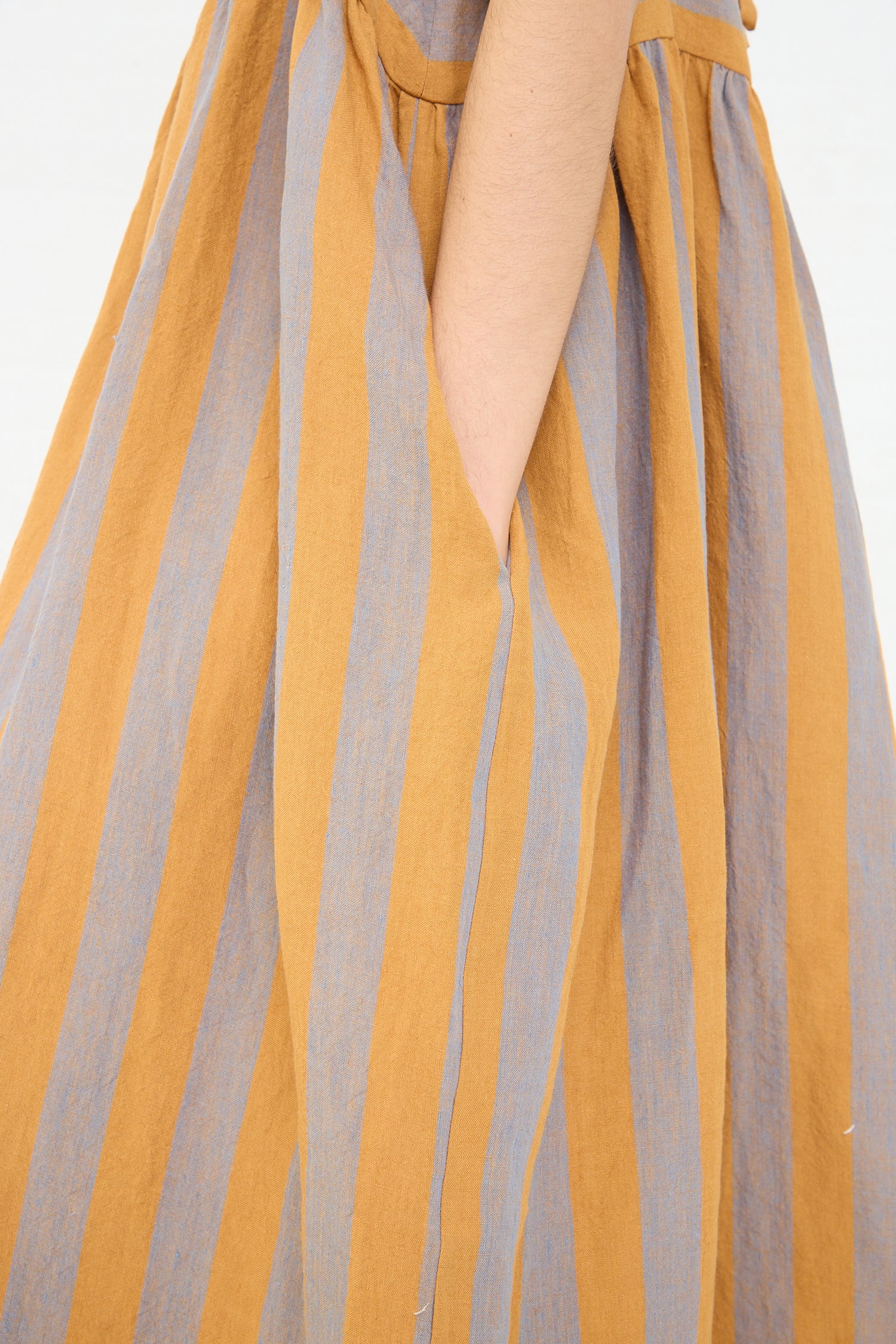 A close-up view of a person's side, with their arm resting against an oversized, Cawley Irish Linen Elba Dress in Bronze.