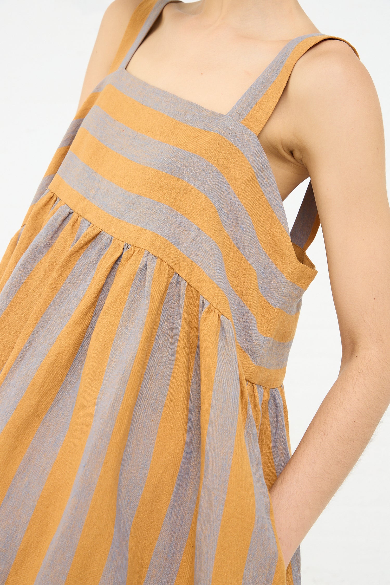 A close-up view of a person wearing a Cawley Irish Linen Elba Dress in Bronze with orange and blue hues, focusing on the upper part of the dress and shoulder area.