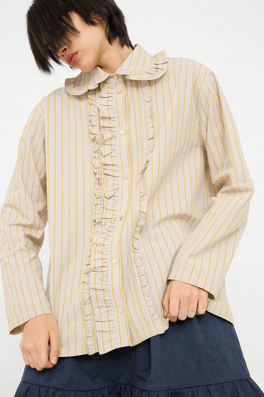 A person wearing a Cawley Japanese Cotton Ruffle Shirt in Sun and Grey with ruffle detailing on the button placket.