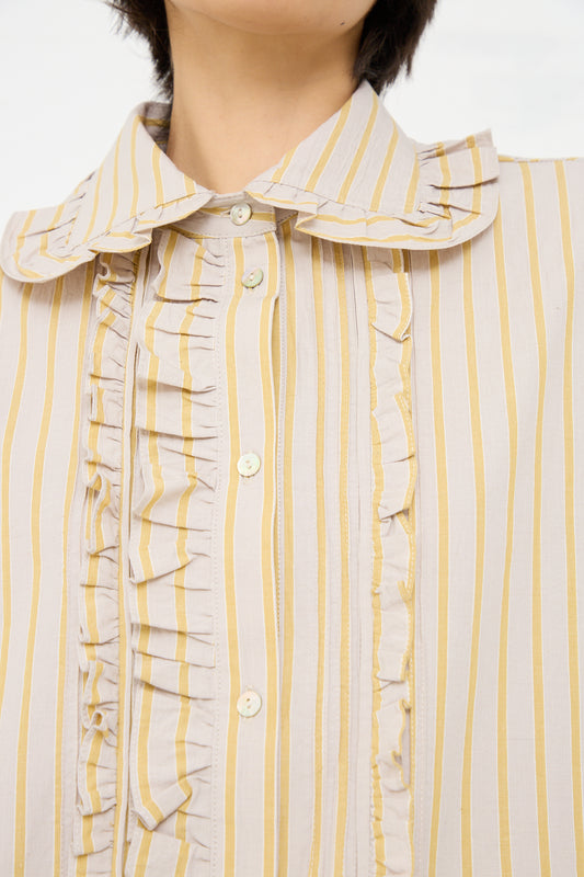 A close-up image of a person wearing a Japanese Cotton Ruffle Shirt in Sun and Grey by Cawley, focusing on the collar area down to the mid-torso.