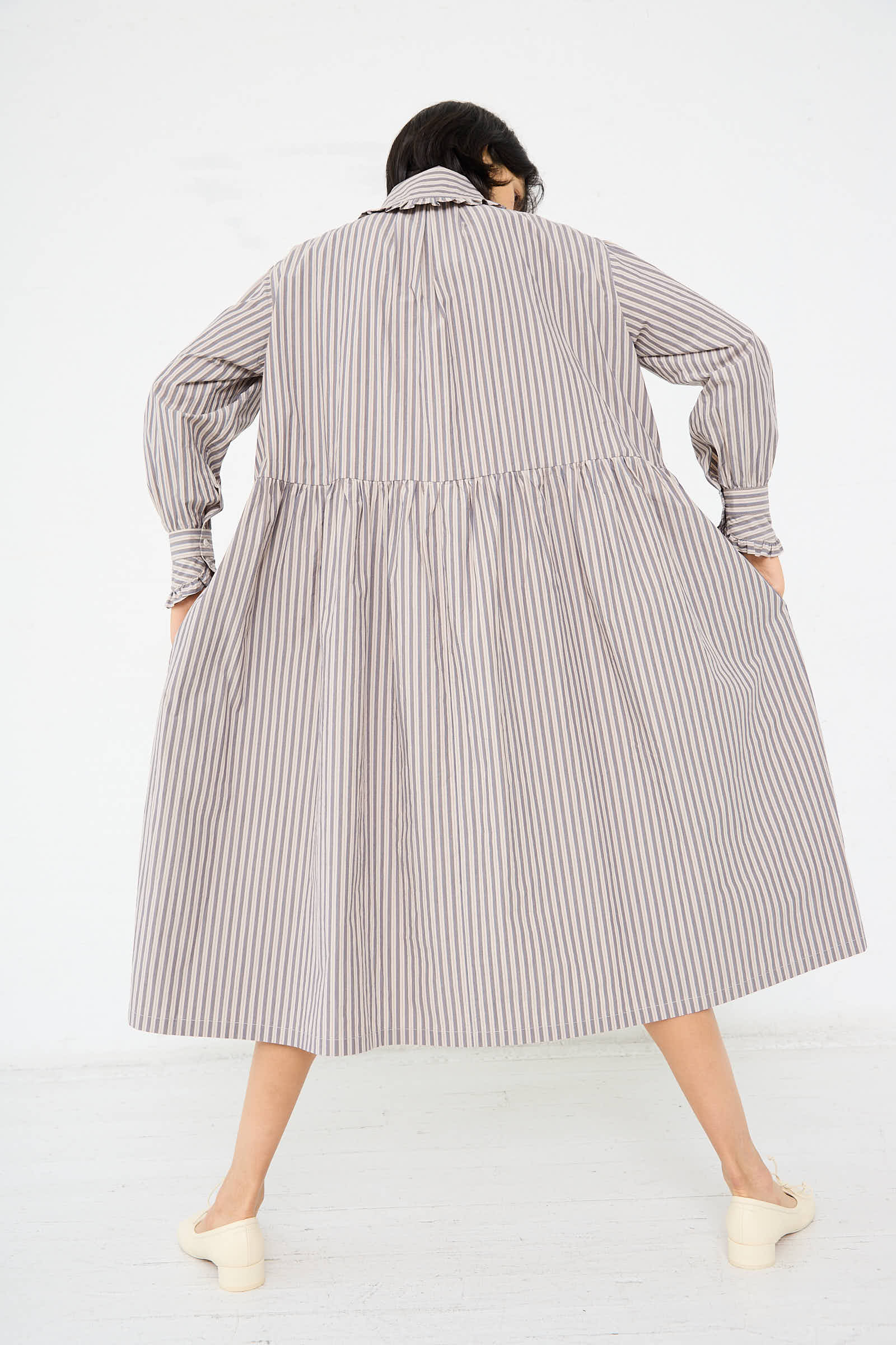 Person wearing the Lydbrook Dress in Natural, Blue and Brown Stripe by Cawley and light-colored shoes, shown from the back against a plain white background.