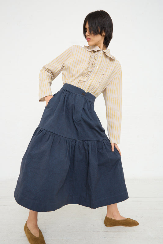 A woman in a yellow striped shirt and a Cawley Japanese Heavy Cotton Patience Big Gathered Skirt in Dark Navy is posing with her hips shifted to one side against a white background.