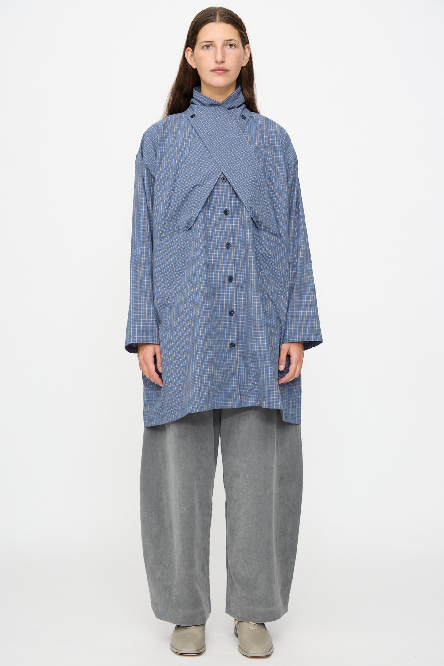 A person stands against a white background wearing the Cawley Japanese Mini Check Cotton Dorothy Dress in Blue.