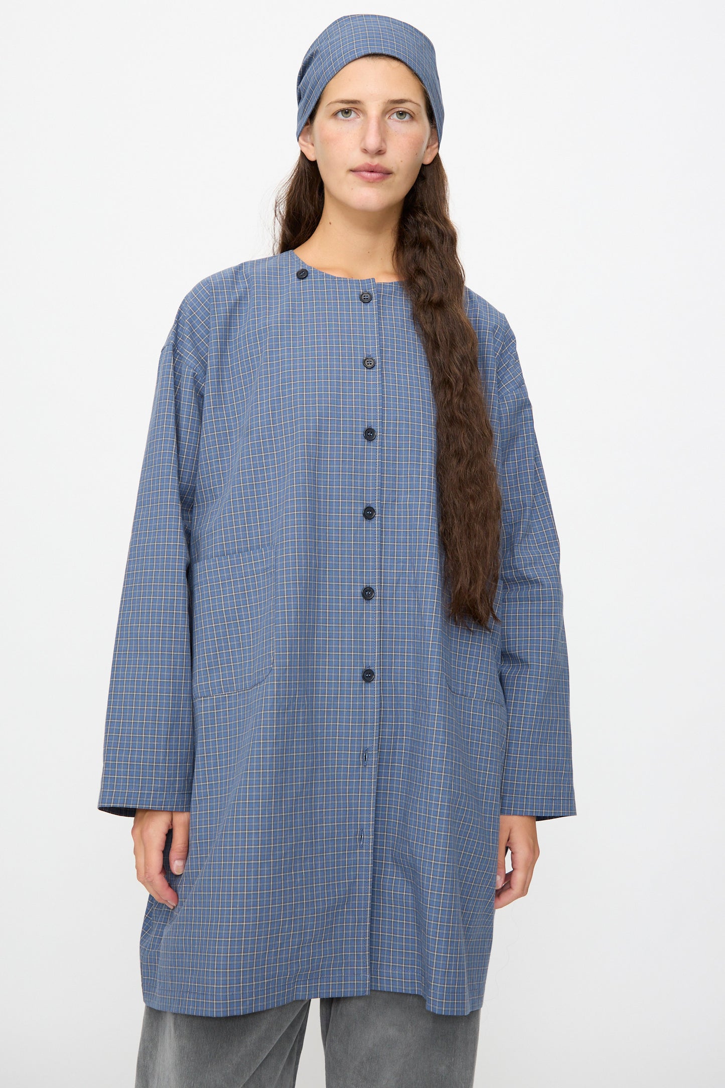 A person wearing the Cawley Japanese Mini Check Cotton Dorothy Dress in Blue, standing against a plain light background.