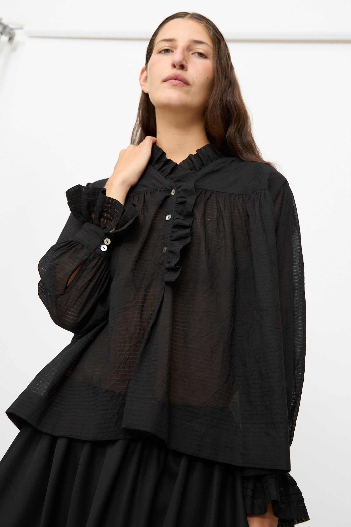 A person with long brown hair wears the Cawley Japanese Sheer Stripe Cotton Sophie Shirt in Midnight, styled with a black skirt, standing against a plain white background.