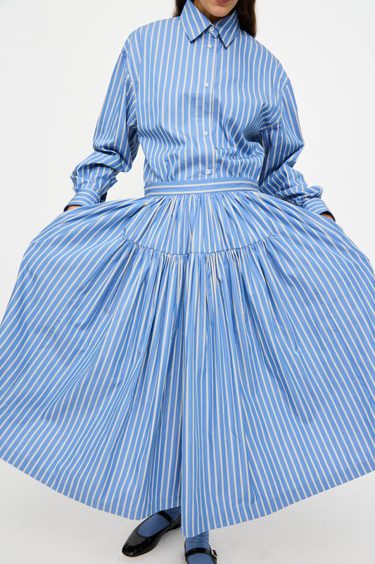 Person wearing the Cawley Japanese Striped Shirting Panel Skirt in Dandelion, with blue and white vertical stripes, holding out the sides.