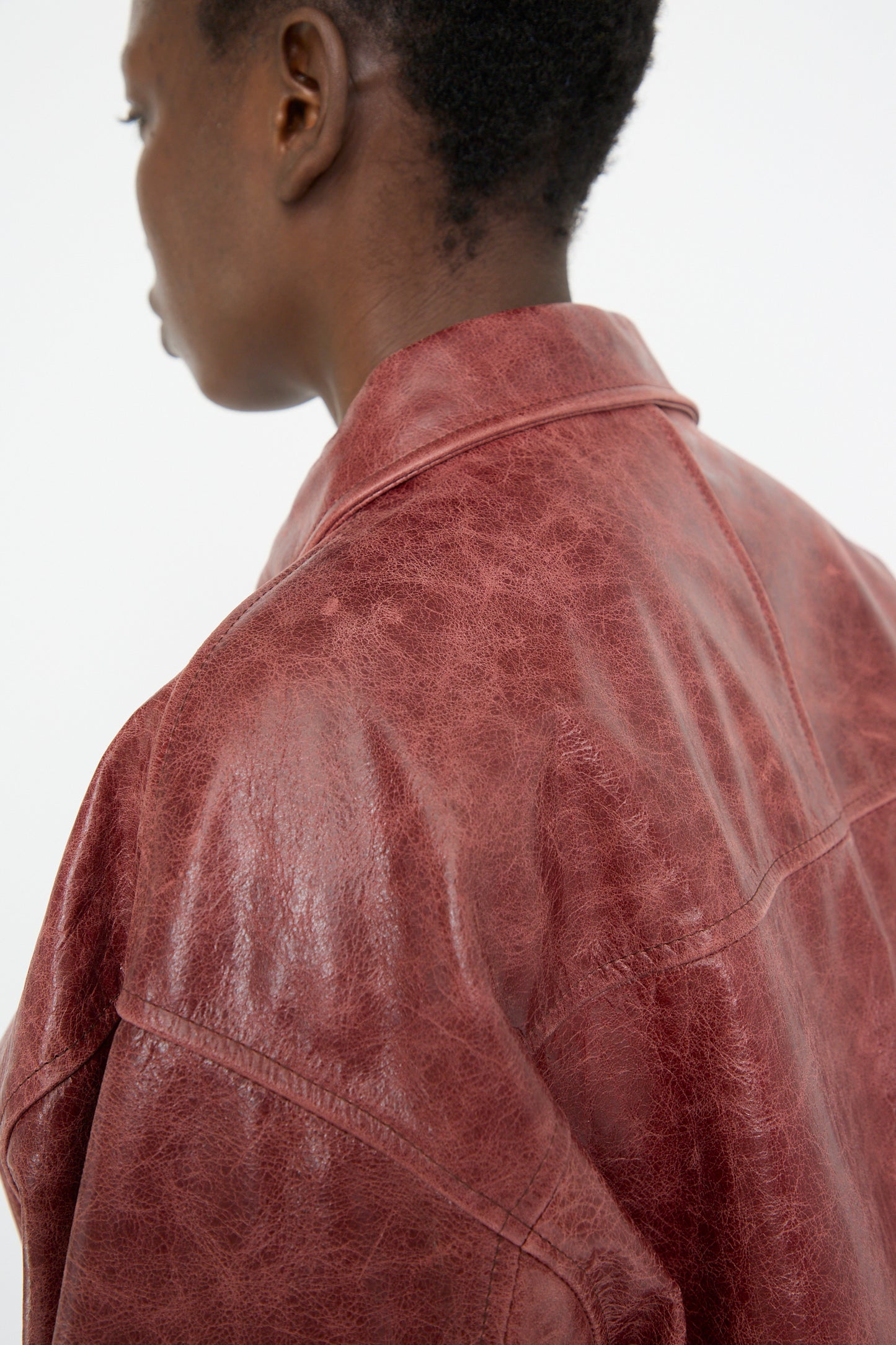 A person wearing Cawley's oversized Leather Flying Jacket in burgundy is shown from the back and side in a neutral setting.