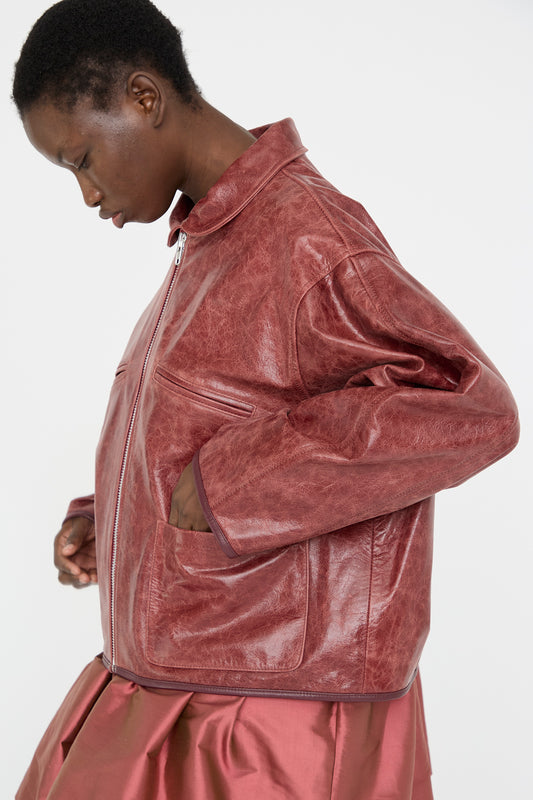 A model in a Cawley Leather Flying Jacket in Burgundy, featuring an oversized fit, poses sideways against a plain background.