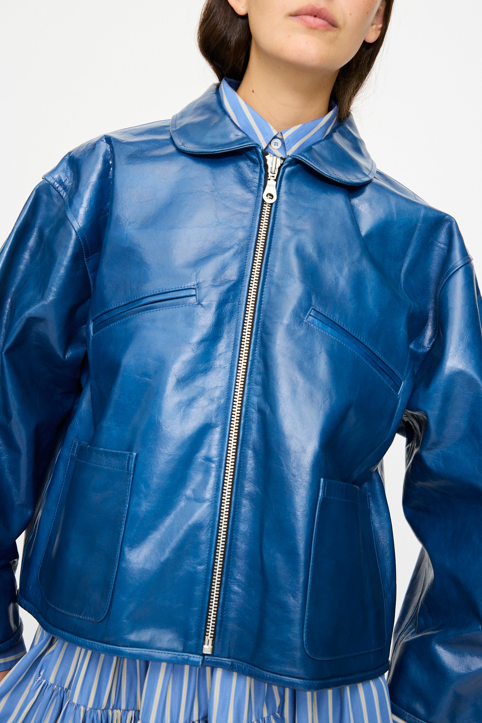 A person wearing the Cawley Leather Flying Jacket in Canada Blue, oversized fit, over a blue and yellow striped shirt, photographed from the waist up.