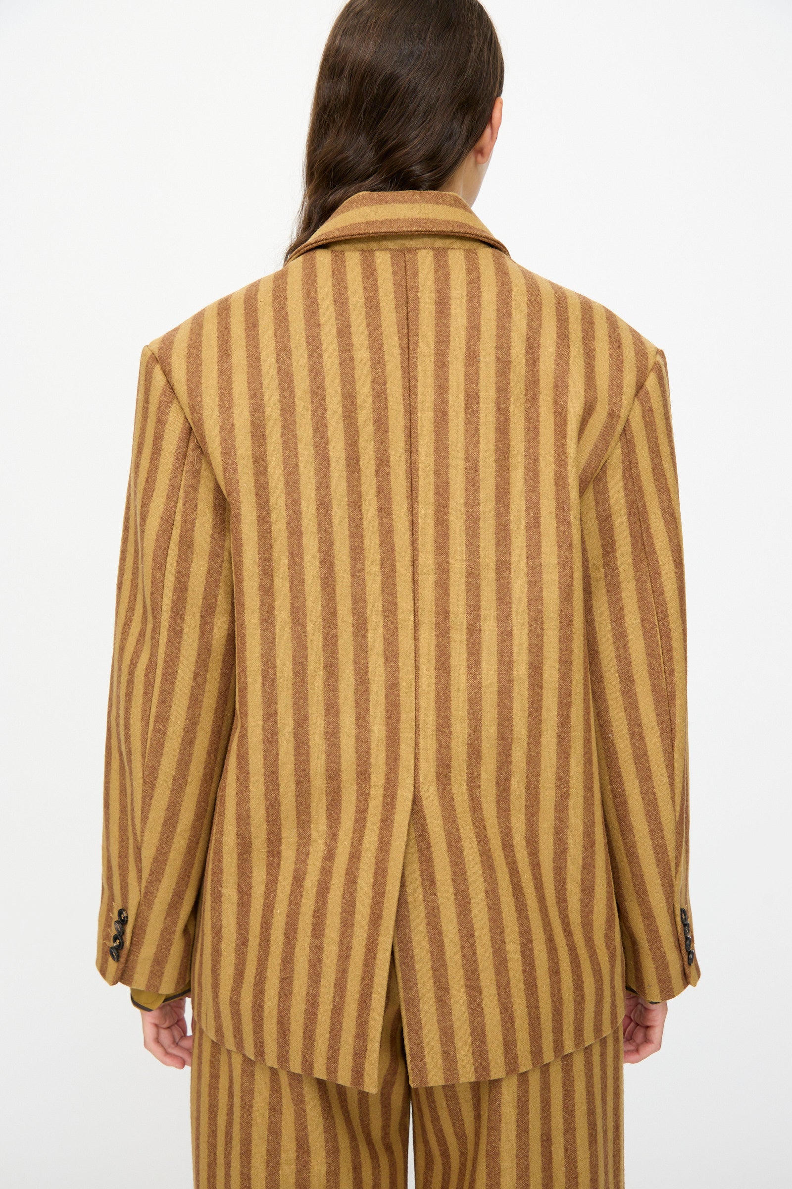 Person shown from the back wearing the Cawley Portuguese Striped Wool Andie Blazer in Goldfinch and Bordeaux with matching pants, set against a plain background.