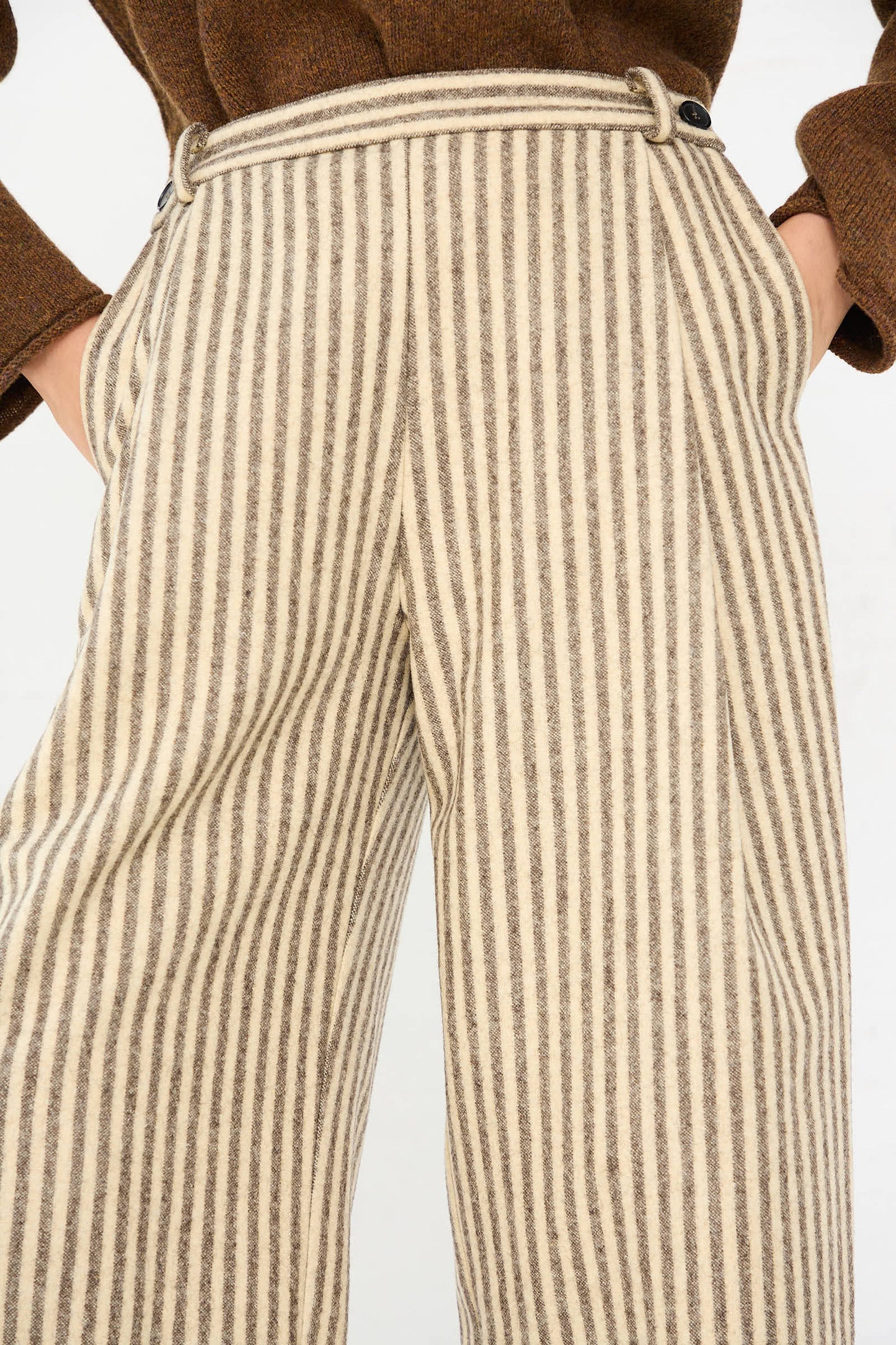 Person wearing relaxed-fit Cawley Portuguese Striped Wool Georgia Trouser in Ecru and Brown with hands in pockets. The top of a brown sweater is partially visible.