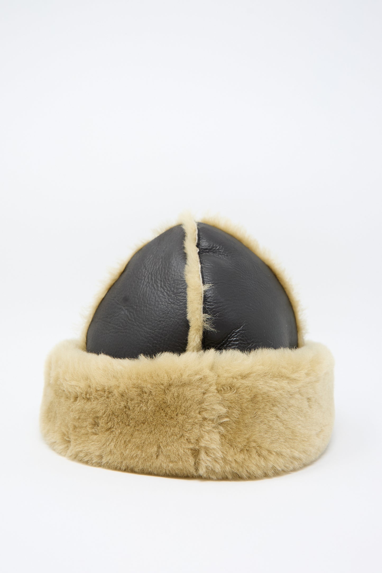 The Sheepskin Leather Seam Hat in Chocolate and Tan by Cawley is displayed upright on a plain white background, featuring a sheepskin trim and fur-lined leather crafted in London.