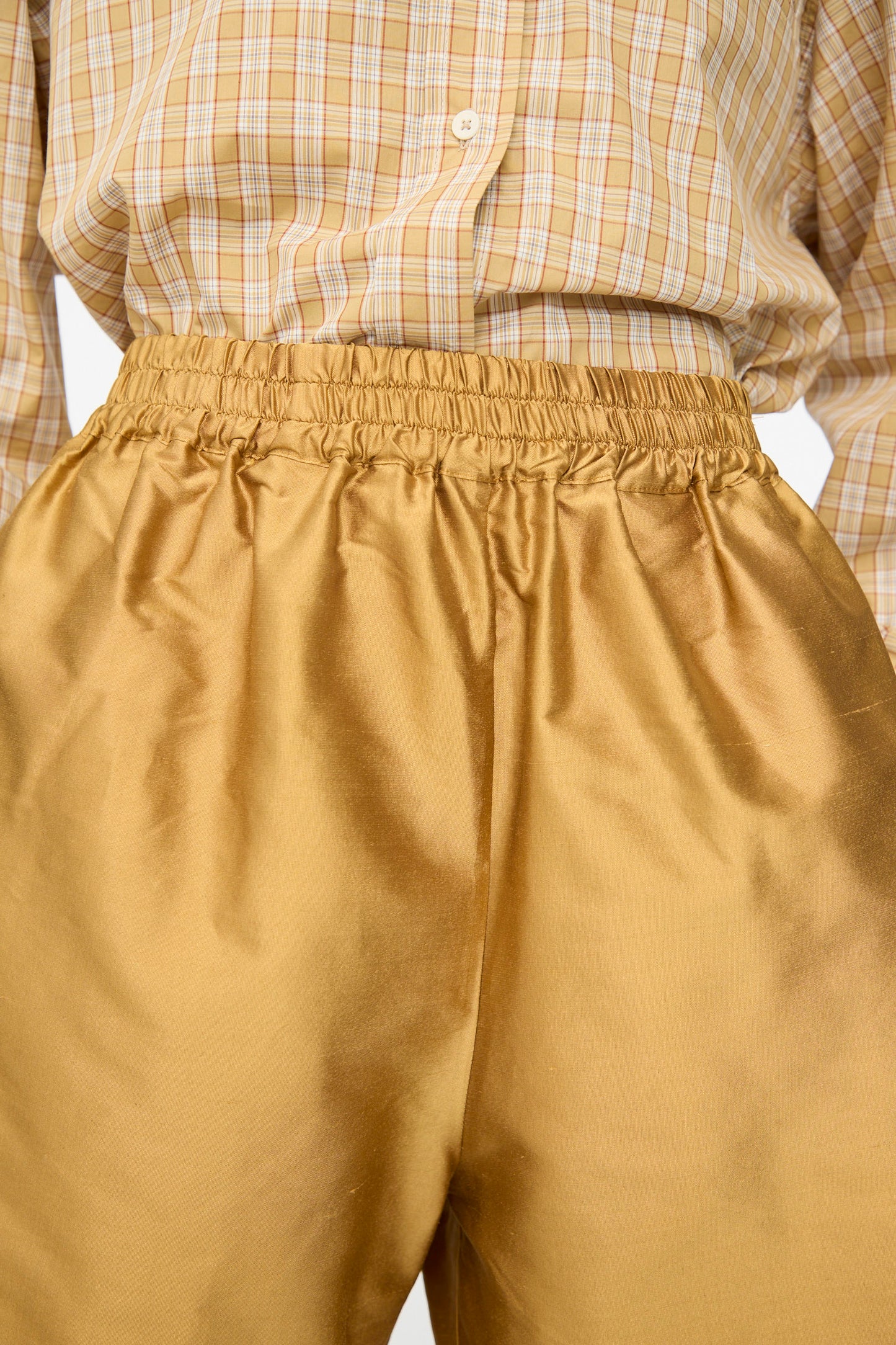 A person wearing a yellow plaid button-up shirt tucked into Cawley's Silk Dupion Hilda Short in Ochre.
