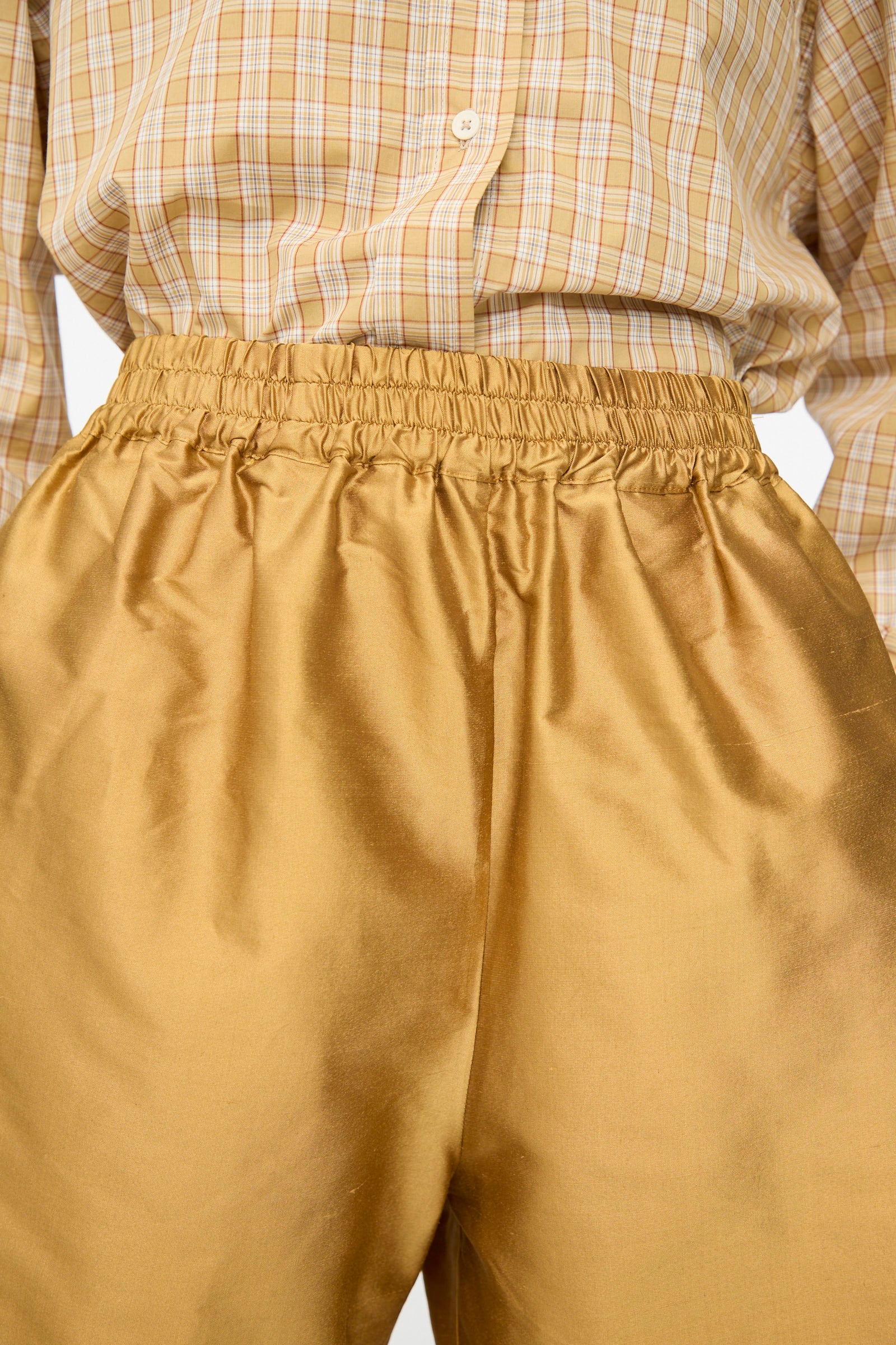 A person wearing a yellow plaid button-up shirt tucked into Cawley's Silk Dupion Hilda Short in Ochre.