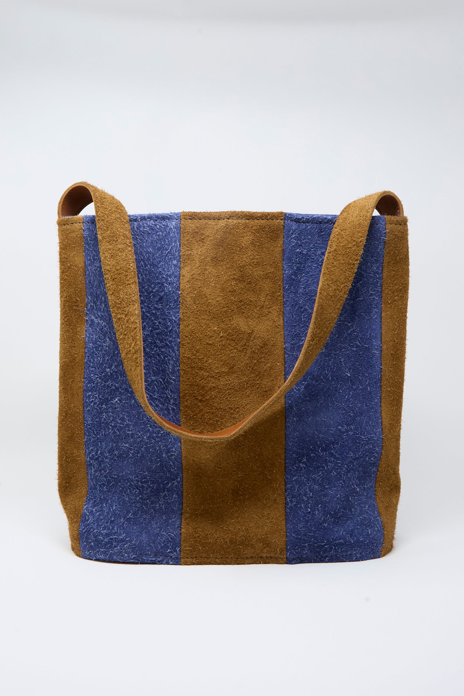 The Cawley Suede Striped Shoulder Bag in Navy and Light Brown features alternating vertical panels of blue and brown suede and a wide shoulder strap, showcased against a plain white background.