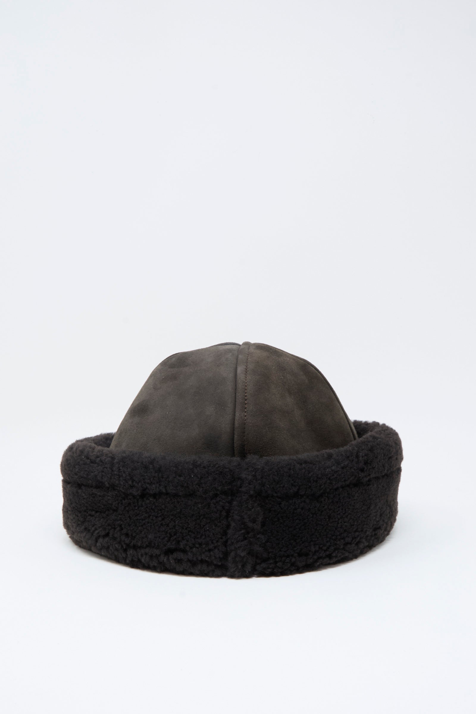 The Cawley Suede Back Curly Hair Cap in Chocolate features a dark brown suede sheepskin design with a rounded crown and thick fur trim, crafted in London and shown on a plain white background.