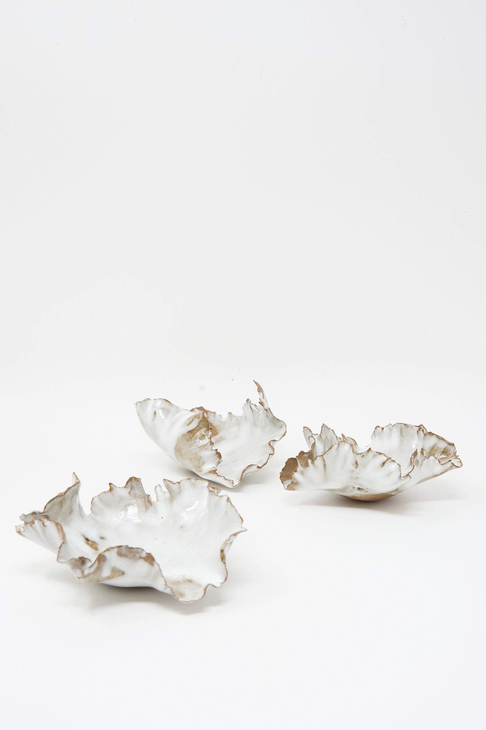 Three irregularly-shaped, white Chala Toprak Wild Petal Incense Holders with wavy, uneven edges are displayed on a plain white background. Each unique piece is handcrafted in NYC, reflecting artisanal craftsmanship and modern design.
