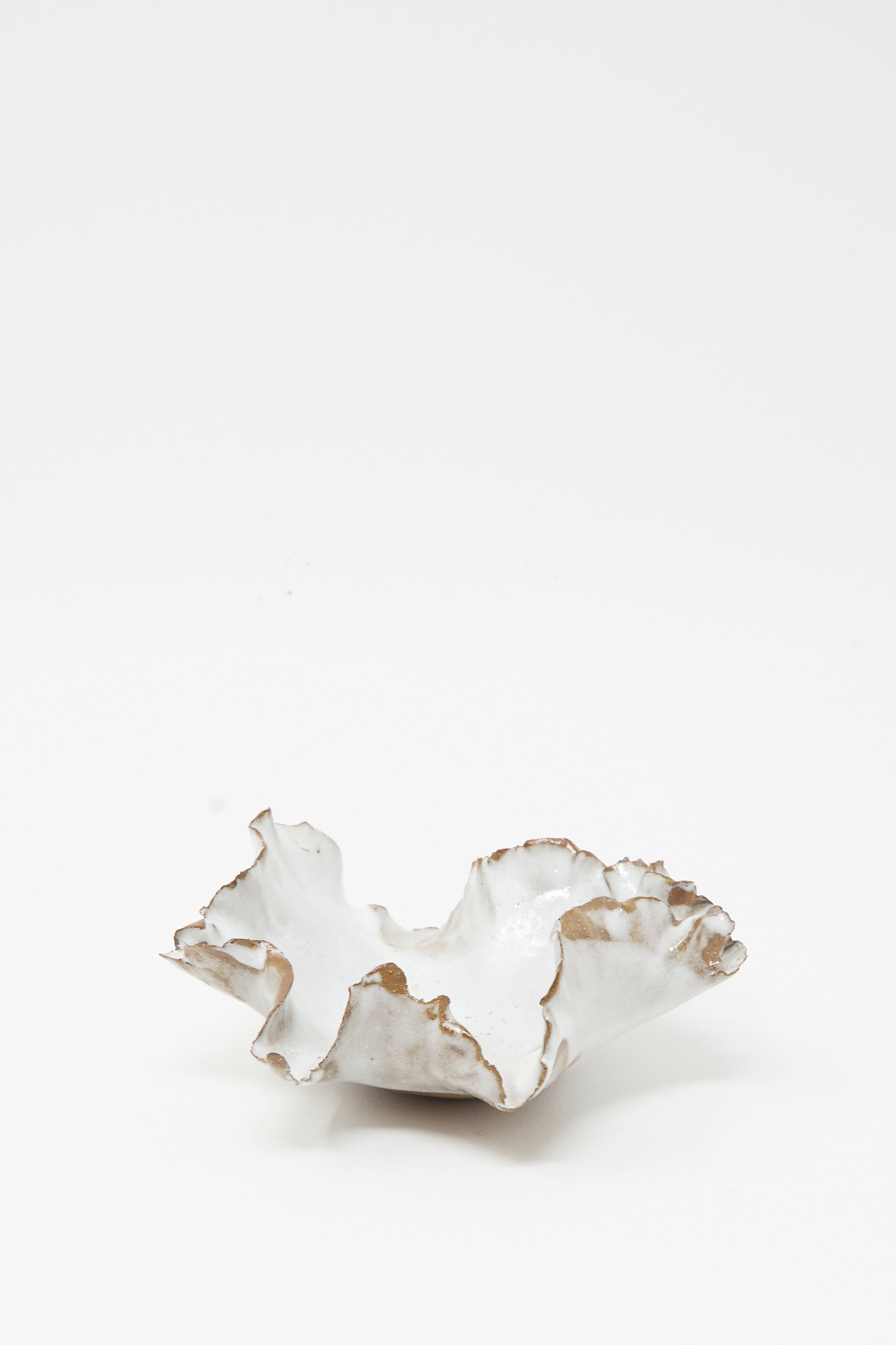 The Wild Petal Incense Holder by Chala Toprak, a white stoneware ceramic piece featuring ruffled, irregular wavy edges and subtle light brown accents, is displayed on a plain white background.