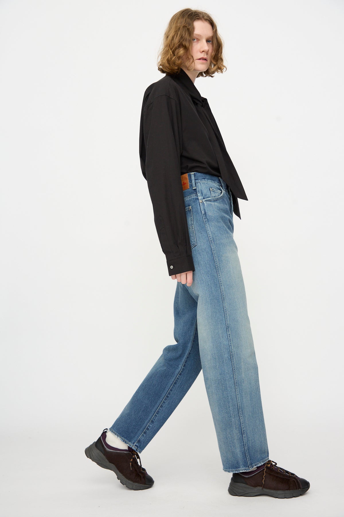 A person wearing a black button-up shirt, white socks, dark shoes, and Chimala 12oz Denim Straight Cut in Work Light Blue jeans stands against a plain white background.