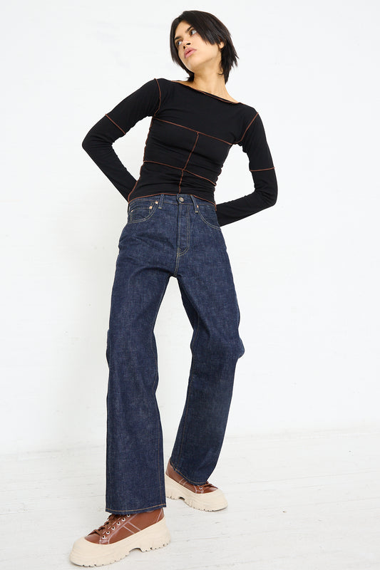 Woman posing in black top and Chimala 13.5 oz. Selvedge Denim Straight Cut in Rinse jeans against a white background.