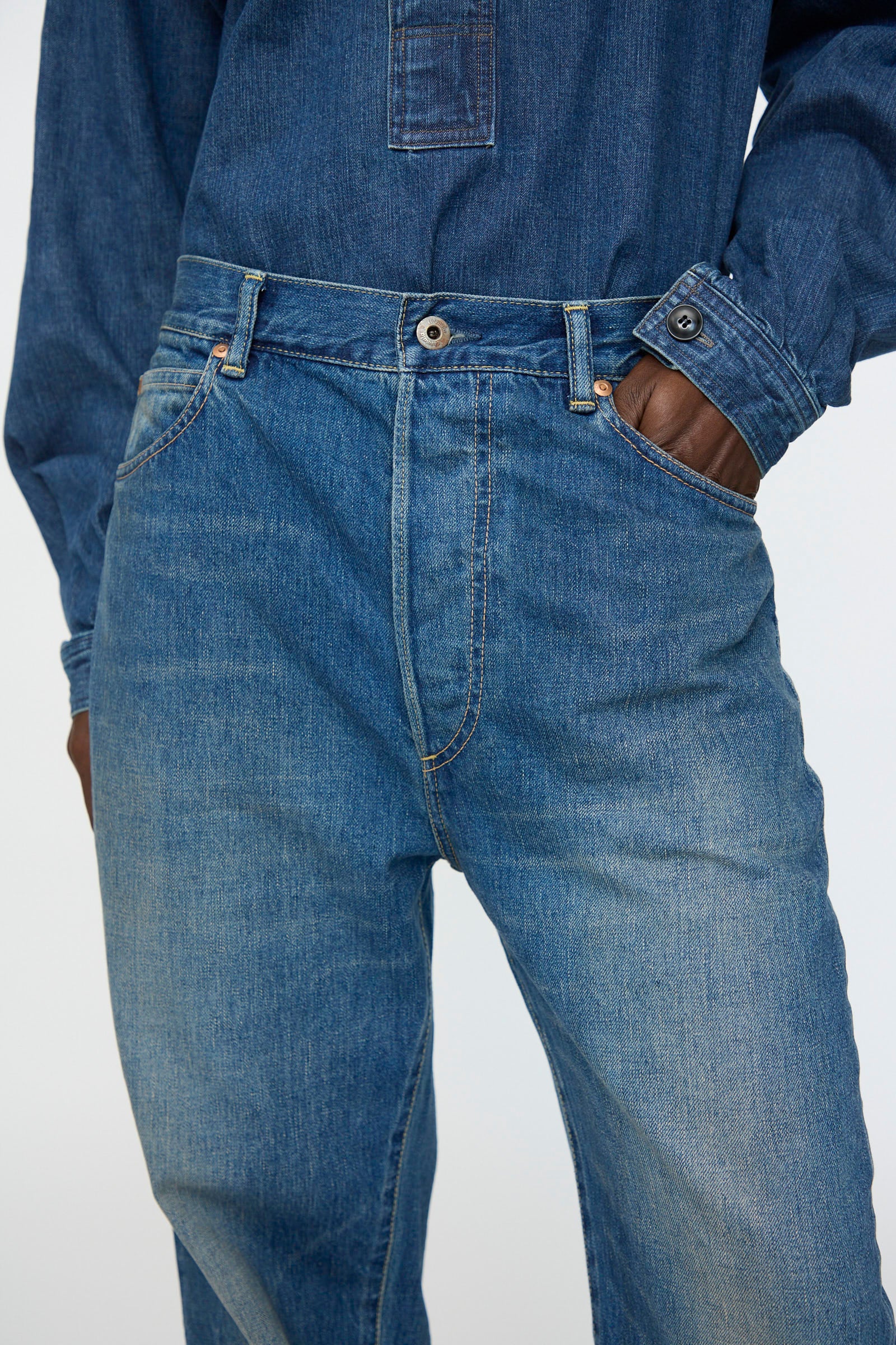 Model wearing Chimala’s 13oz. Selvedge Denim Monroe Cut in Dark Distress, blue denim shirt tucked in, one hand in the pocket; shown from waist to mid-thigh.