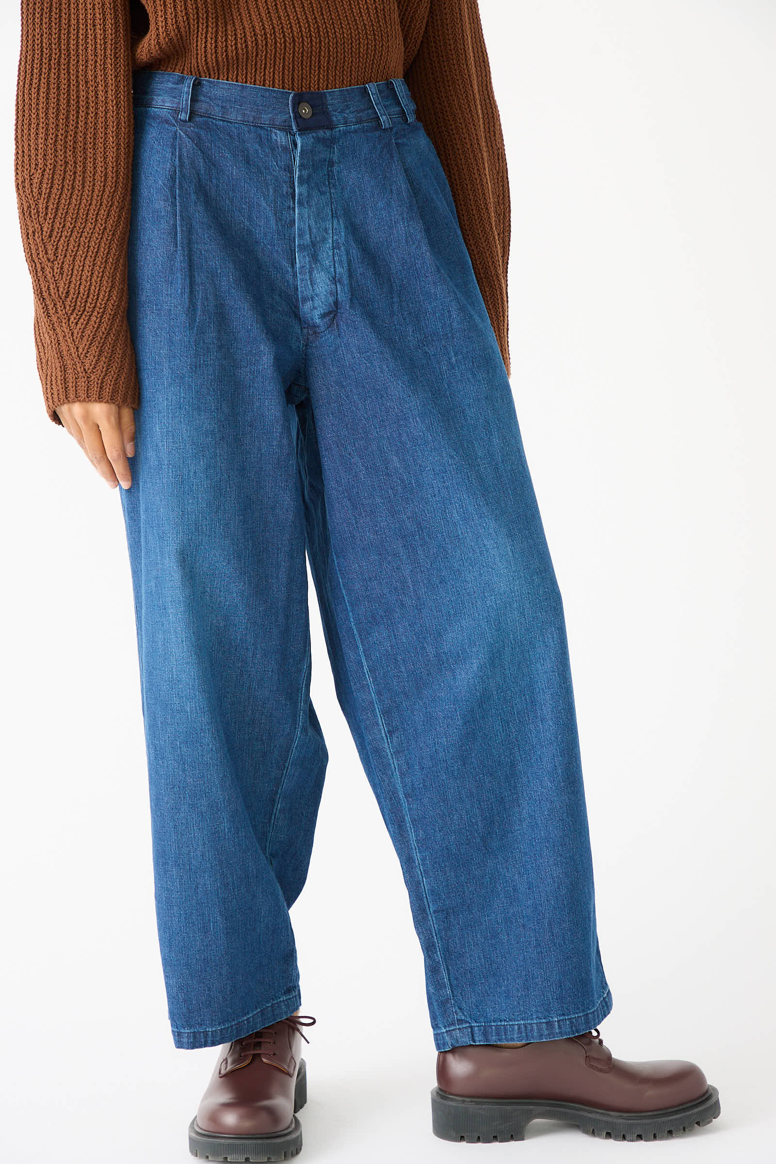 Person wearing Chimala 8oz. Denim Trouser in Indigo, a brown sweater, and brown shoes stands in front of a plain background.